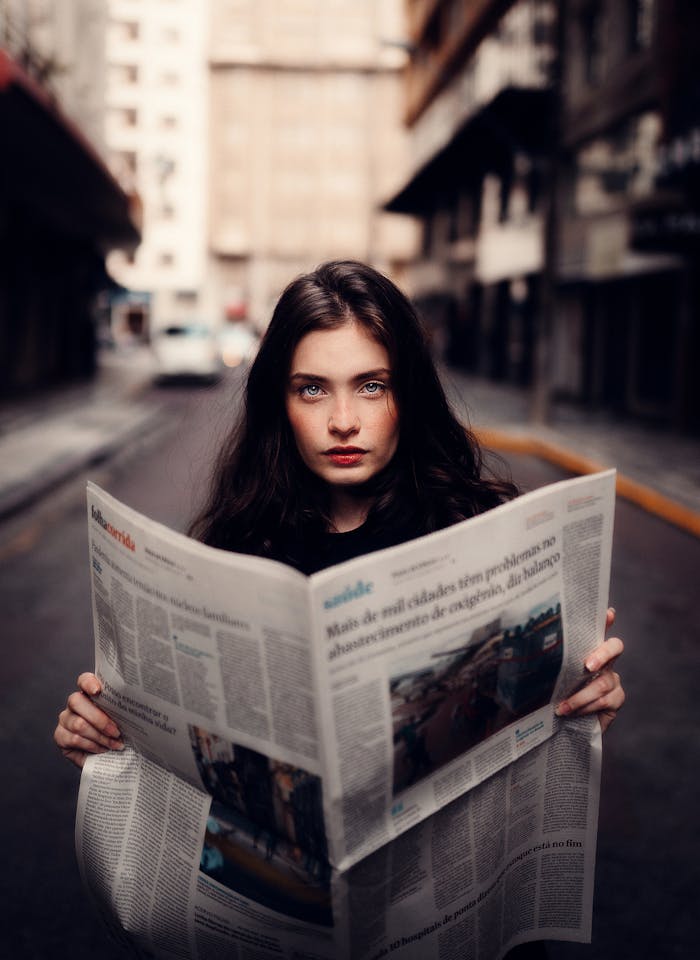 home-hero Portrait of a woman standing in an urban street holding a newspaper.